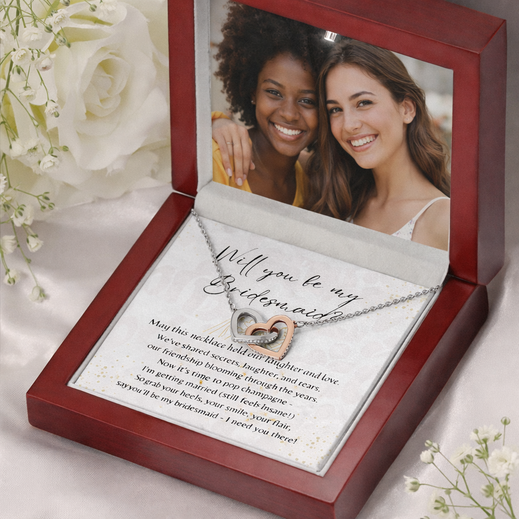 Open wooden box displaying a heart-shaped necklace and a card asking someone to be a bridesmaid with a photo above.