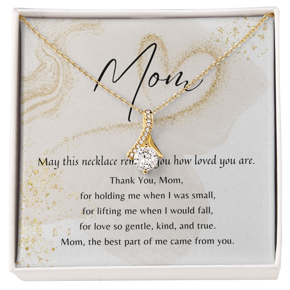 Gold ribbon-shaped necklace with cubic zirconia pendant on gift card with a heartfelt message for Mom in a presentation box