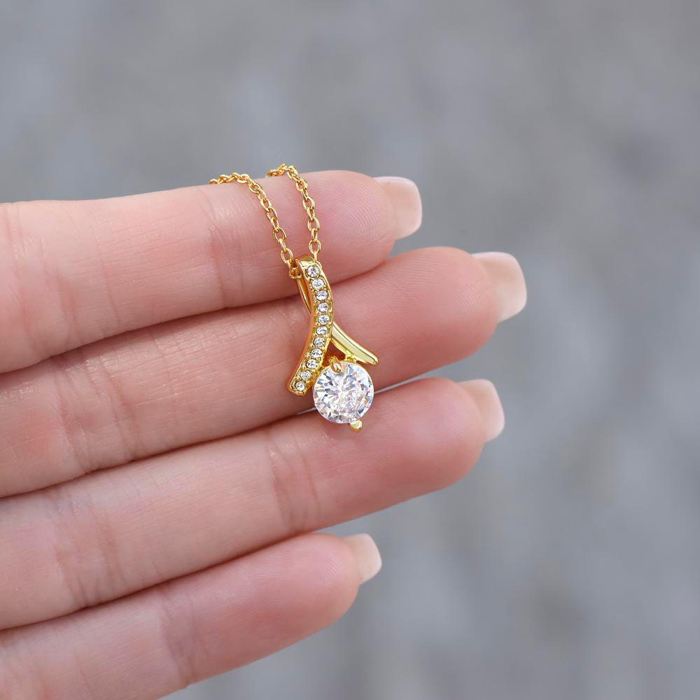 Hand holding a gold-plated Alluring Beauty Necklace pendant with sparkling cubic zirconia crystals