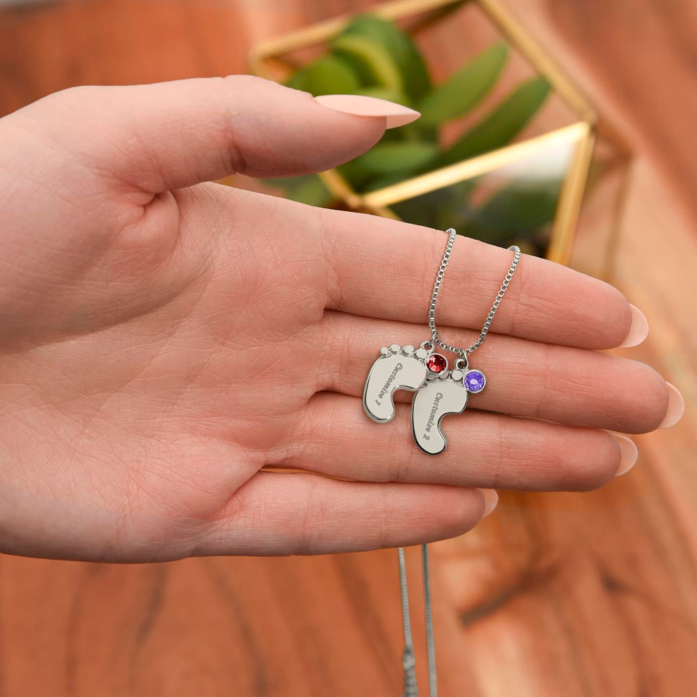 Personalized Engraved Baby Feet Necklace with Birthstone for New Mom (2-4 Charms) – A Meaningful Gift for a New Mom | Stainless Steel or 18k Yellow Gold Finish shown in hand with two charms and birthstones