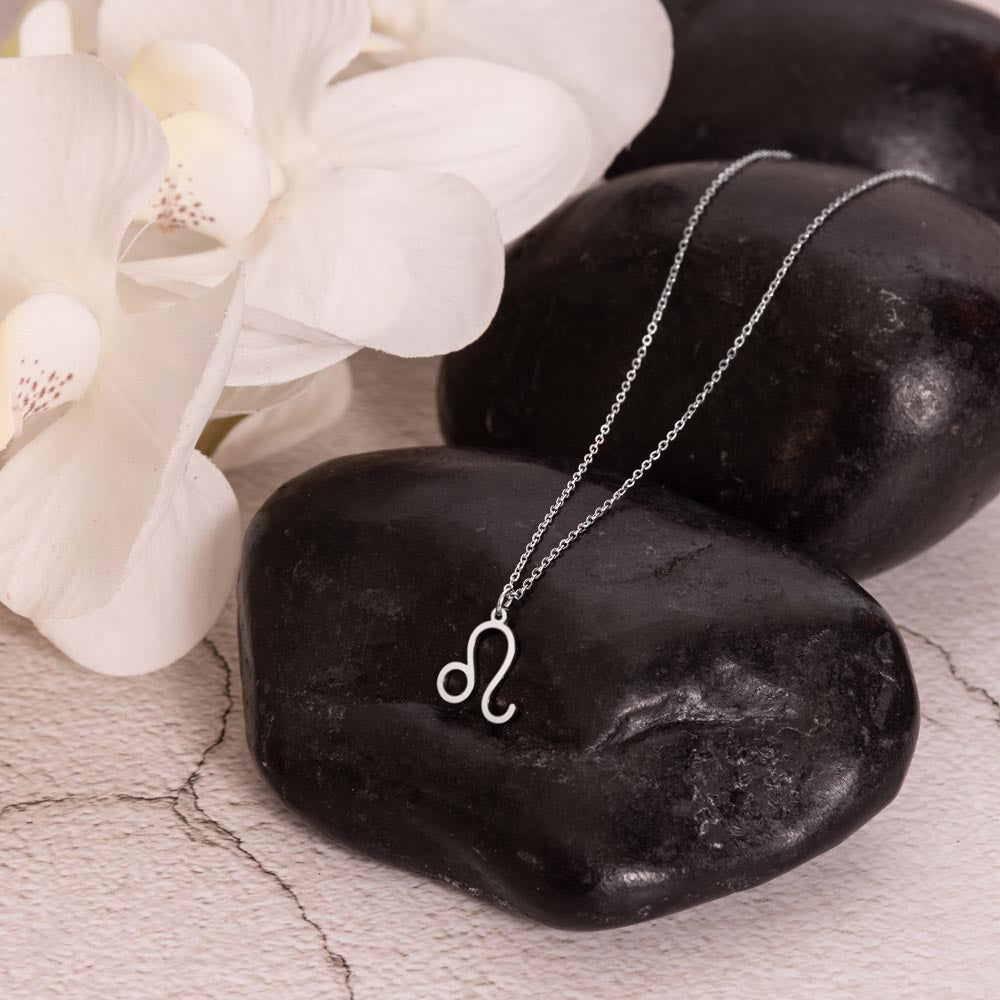 Leo Zodiac Symbol Necklace for Girls – A Meaningful Gift for a Leo Girl | Stainless Steel or 18k Yellow Gold Finish displayed on black stones with white flowers