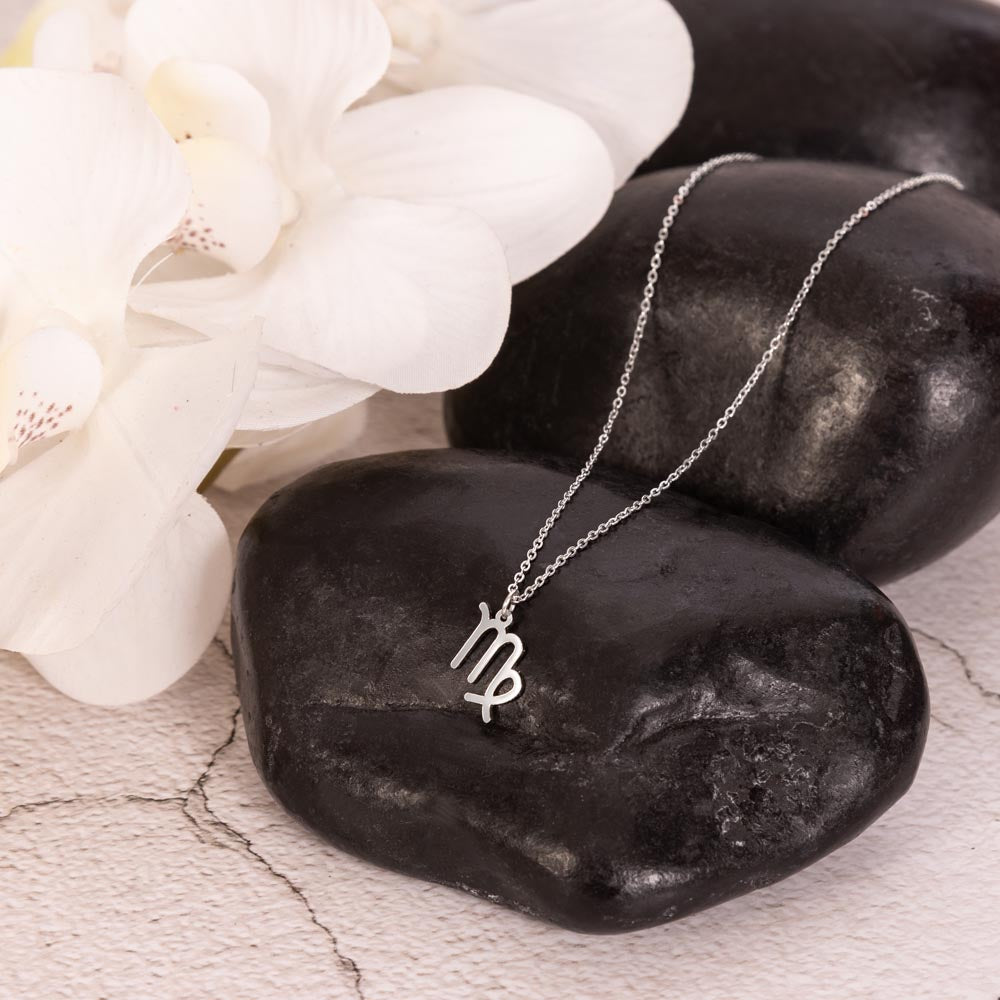 Virgo Zodiac Necklace for Women – Astrology Gift with silver pendant resting on smooth black stones and white orchids nearby