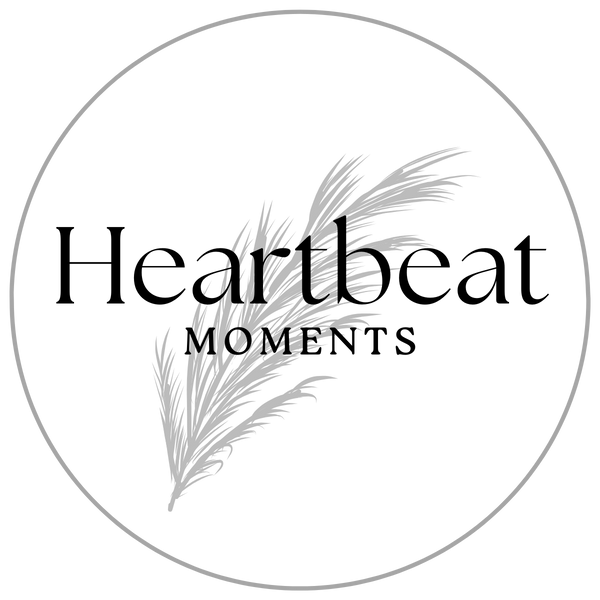 Circle logo featuring stylized feather design with partial text "the artle MOM" in muted gray tones on transparent background.